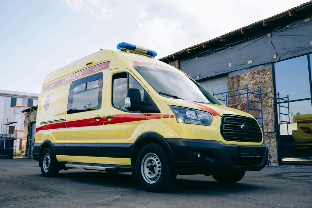 pexels-photo-28123708-28123708 Bright yellow ambulance parked outdoors in an urban environment.