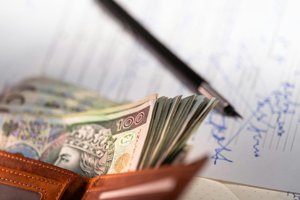 pexels-photo-35501871-35501871 Stack of Polish zloty banknotes with pen and document, financial concept.