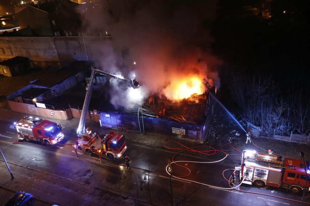 pexels-photo-11696063-11696063 Firefighters battling an urban fire at night with fire trucks and hoses.
