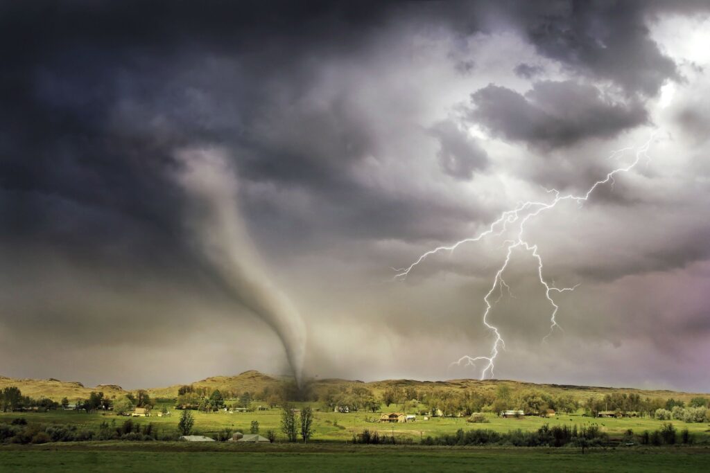 pexels-photo-1446076-1446076 A powerful tornado and vibrant lightning striking over a rural countryside landscape.