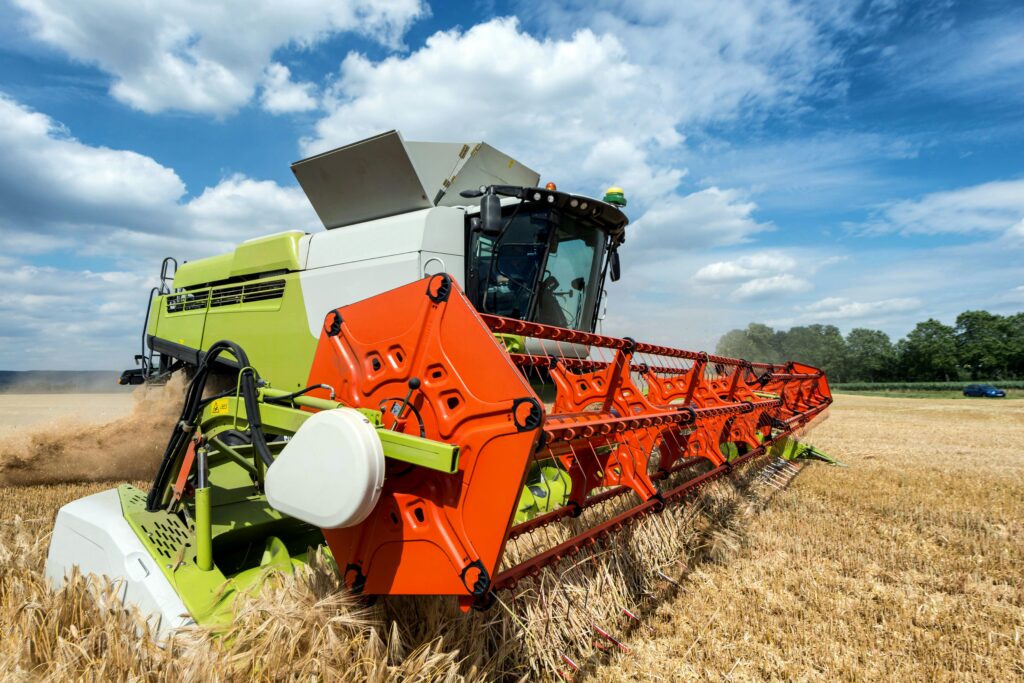 pexels-photo-20884617-20884617 A bright image of a combine harvester working in a golden wheat field under a clear blue sky.