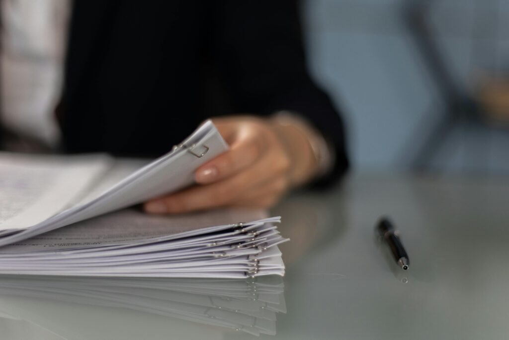 pexels-photo-6077600-6077600 Close-up of a professional organizing a stack of documents on a desk.