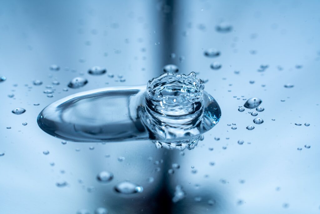 pexels-photo-8349868-8349868 Macro shot capturing a water droplet splash creating ripples on a reflective surface.